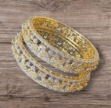 Two gold and diamond-studded bangles on a wooden surface