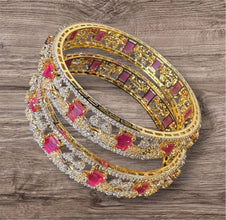 Gold bangles with red stones on a wooden surface