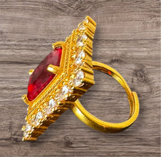 Gold ring with a red gemstone on a wooden surface