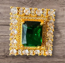 Gold frame with emerald and diamonds on a wooden surface