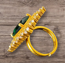 Gold ring with green gemstone on a wooden surface