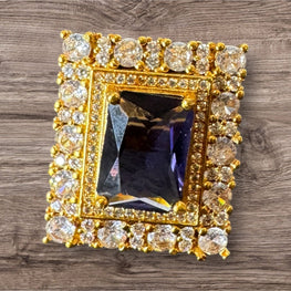 Gold-framed jewelry with central gemstone on a wooden surface