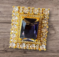 Gold-framed jewelry with central gemstone on a wooden surface