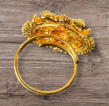 Gold ring with intricate design on a wooden surface