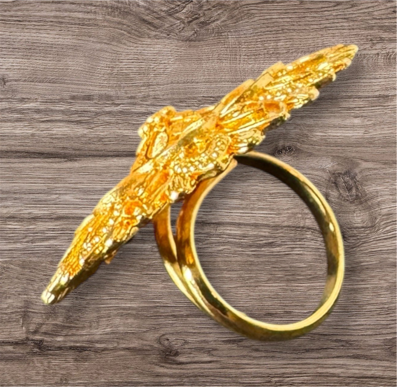 Gold ring with decorative design on a wooden surface