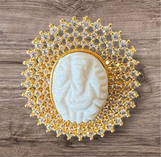 Decorative ring with a central ganesh muga and gold and crystal embellishments on a wooden surface