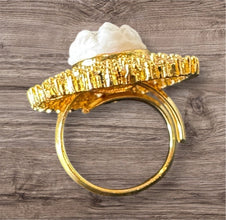 Gold ring with a white stone on a wooden surface